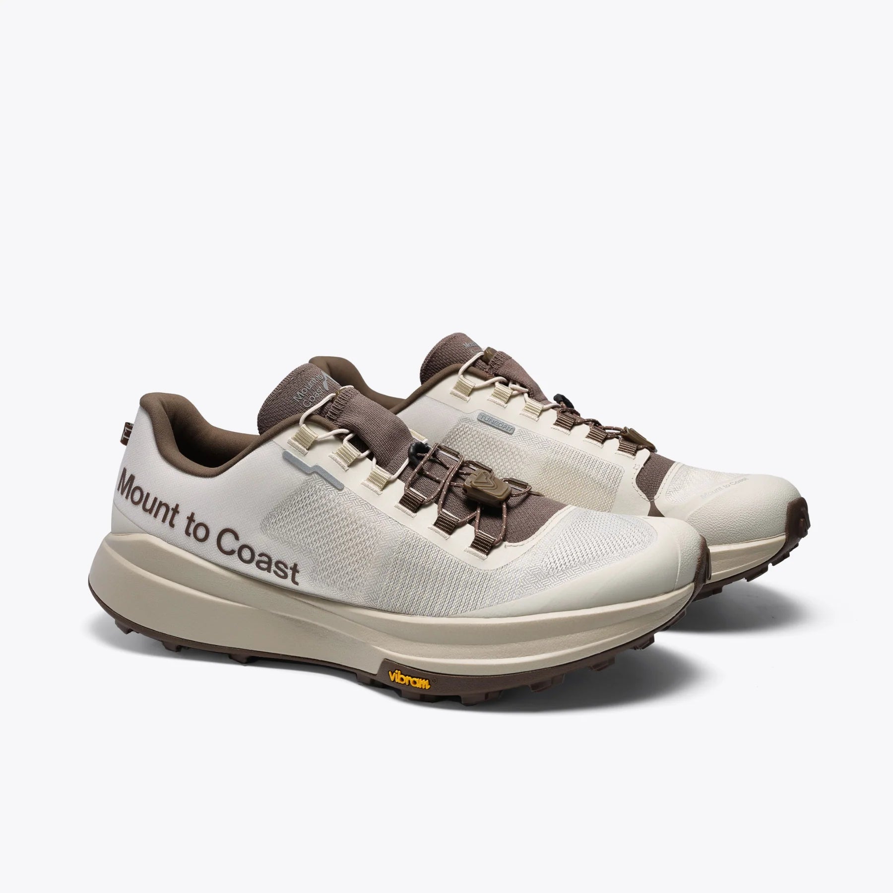 Mount to Coast T1 trail running shoes in cream and brown colorway, featuring Vibram outsole and brand name.
#Color_dune