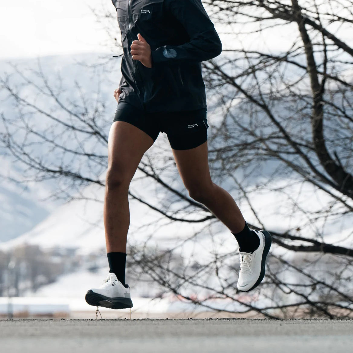 Runner wearing S1 white running shoes, demonstrating performance footwear for road and trail. #Color_white|black